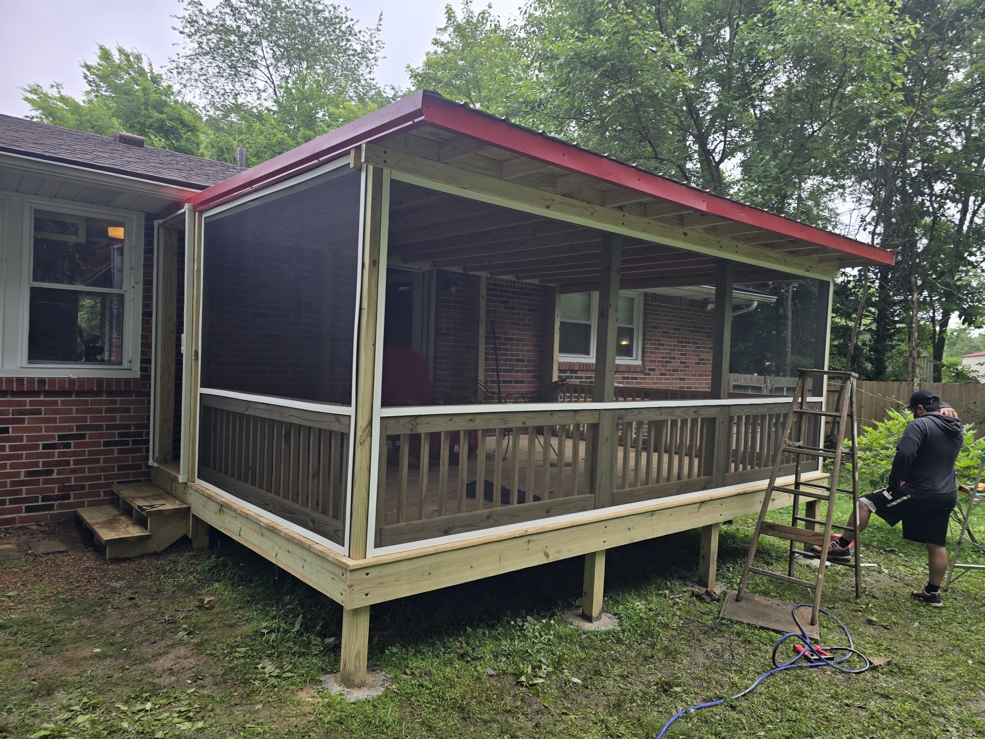 Finished screened-in porch addition with wood deck framing and red metal roof